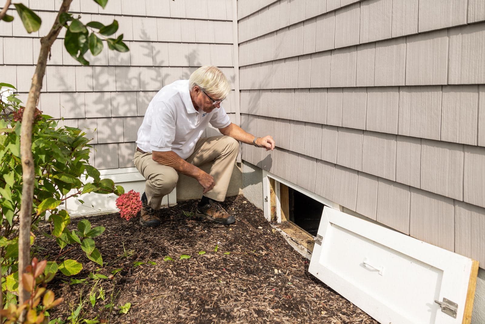 Technician inspecting a crawlspace access for ductwork